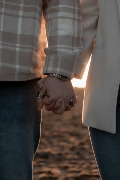 Liefde, love shoot, golden hour Twee mensen houden elkaars hand vast tegen een zonsondergang.